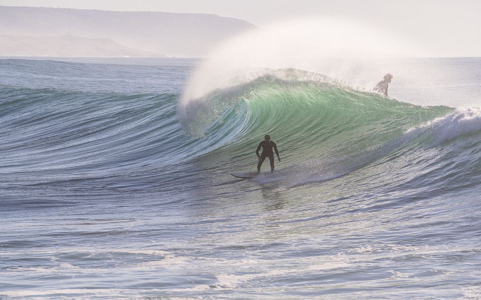 A surfer under a curling wave at Imsouane, Morocco.