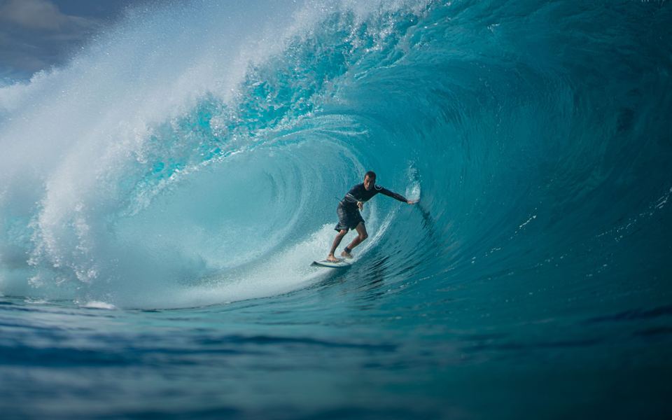 A surfer inside a deep blue barrel at Puerto Escondido, Mexico.
