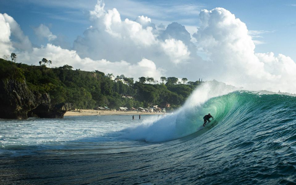 A surfer deep in a long left at Uluwatu, Bali, below the cliffs.